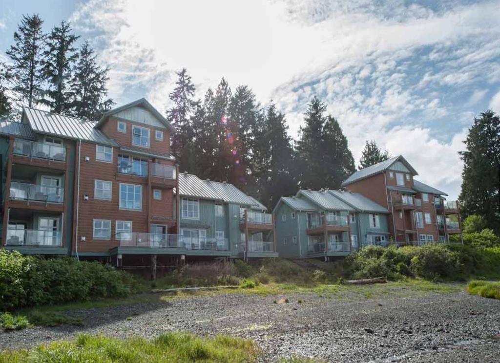 a row of apartment buildings with a mountain in the background at Luxury Oceanfront Condo by OnlyBC 101 in Tofino
