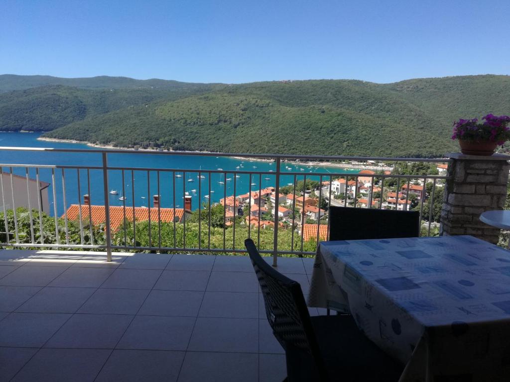 a table and chairs on a balcony with a view of the water at Apartments Alma in Rabac