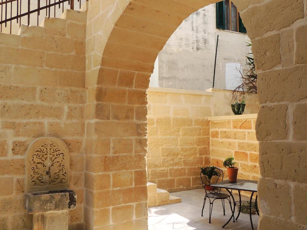 an archway in a stone wall with a table and chairs at Le Luminarie B&B in Lecce