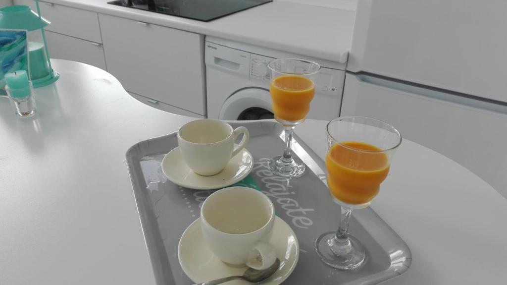dos vasos de zumo de naranja y dos tazas de café en Apartamento Calero, en Puerto Calero