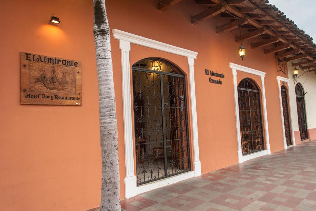 an orange building with doors and a palm tree at El Almirante in Granada