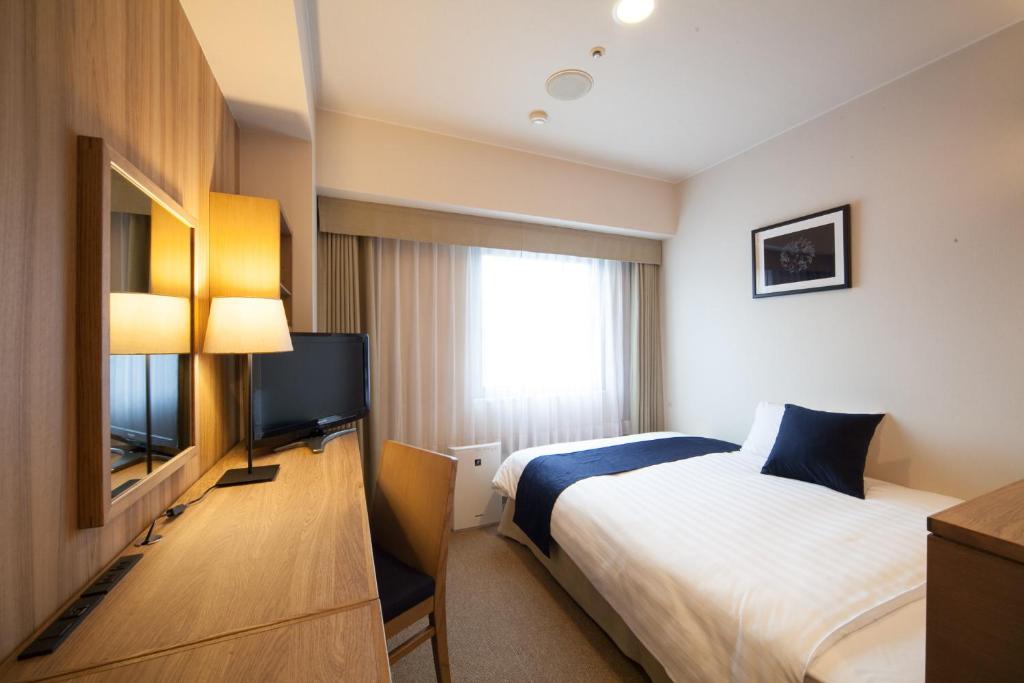 a hotel room with a bed and a flat screen tv at Hotel St Palace Kurayoshi in Kurayoshi