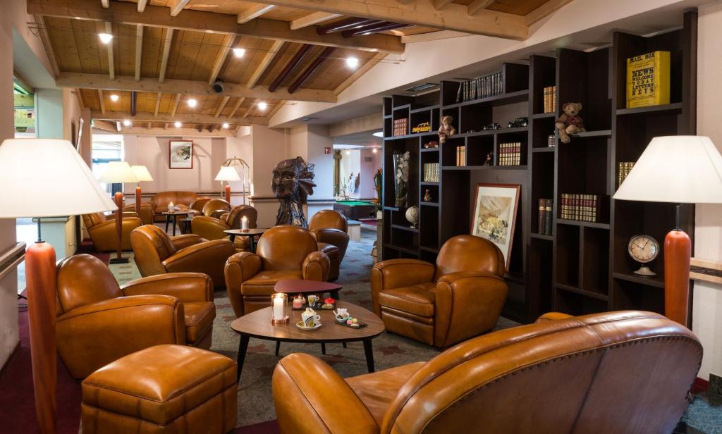a waiting room with brown leather chairs and tables at Hotel Les Vallées Labellemontagne in La Bresse