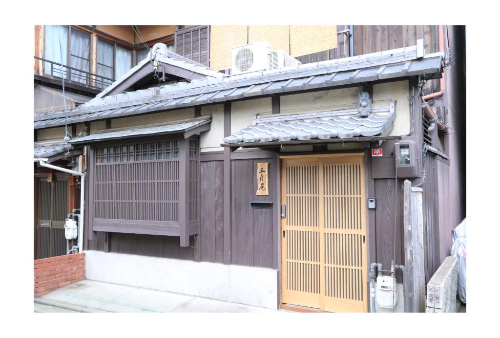 - un bâtiment avec une porte en bois et une fenêtre dans l'établissement Satsukian, à Kyoto