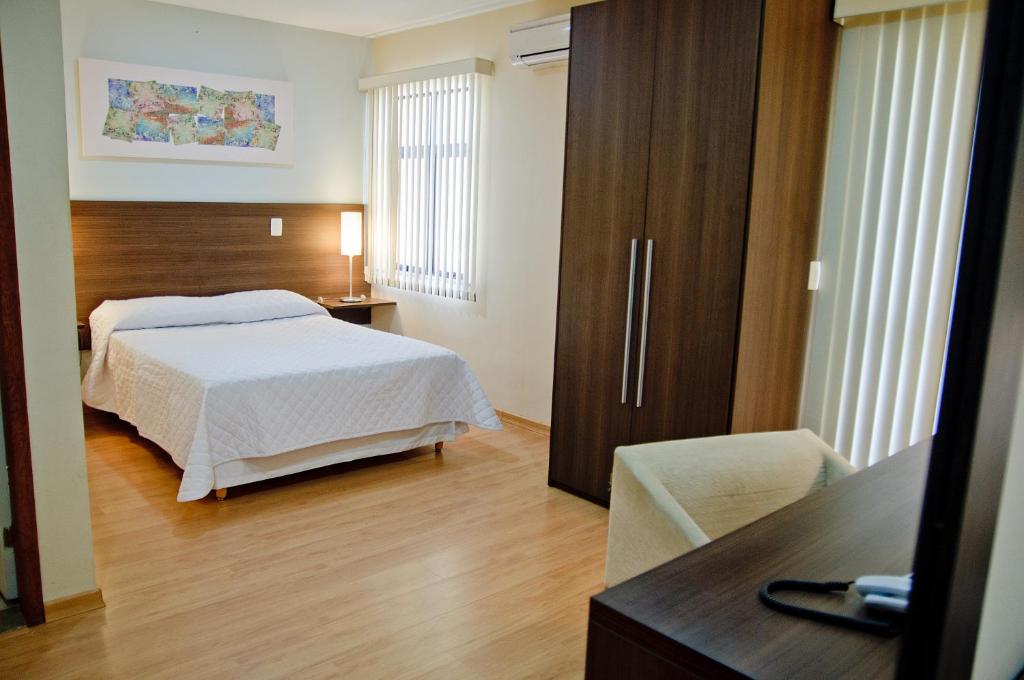 a hotel room with a bed, desk and a television at Mont Blanc Apart Hotel Nova Iguaçu in Nova Iguaçu