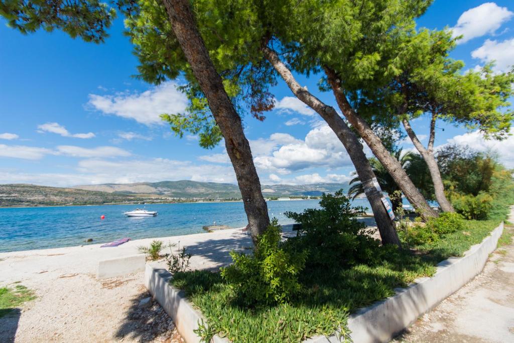 una playa con árboles y un barco en el agua en Apartman Maja, en Trogir