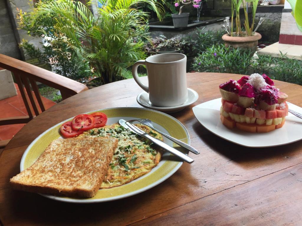 un tavolo con un piatto di cibo con pane tostato e una tazza di caffè di Wayan Guest House ad Ubud