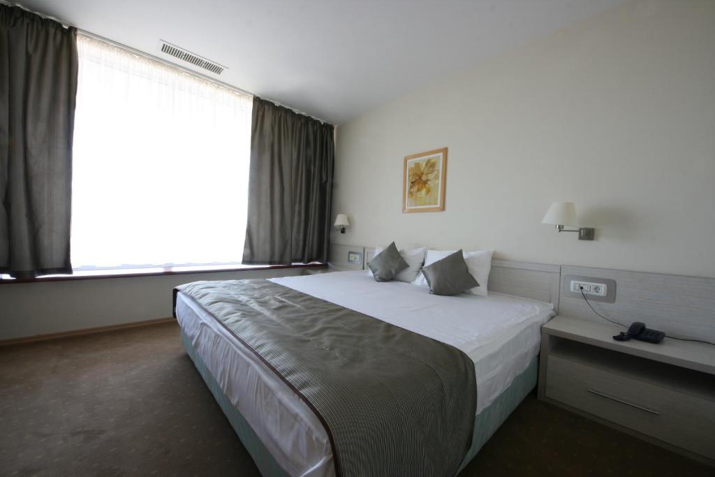 ein Hotelzimmer mit einem großen Bett und einem Fenster in der Unterkunft Savoy Hotel in Timişoara