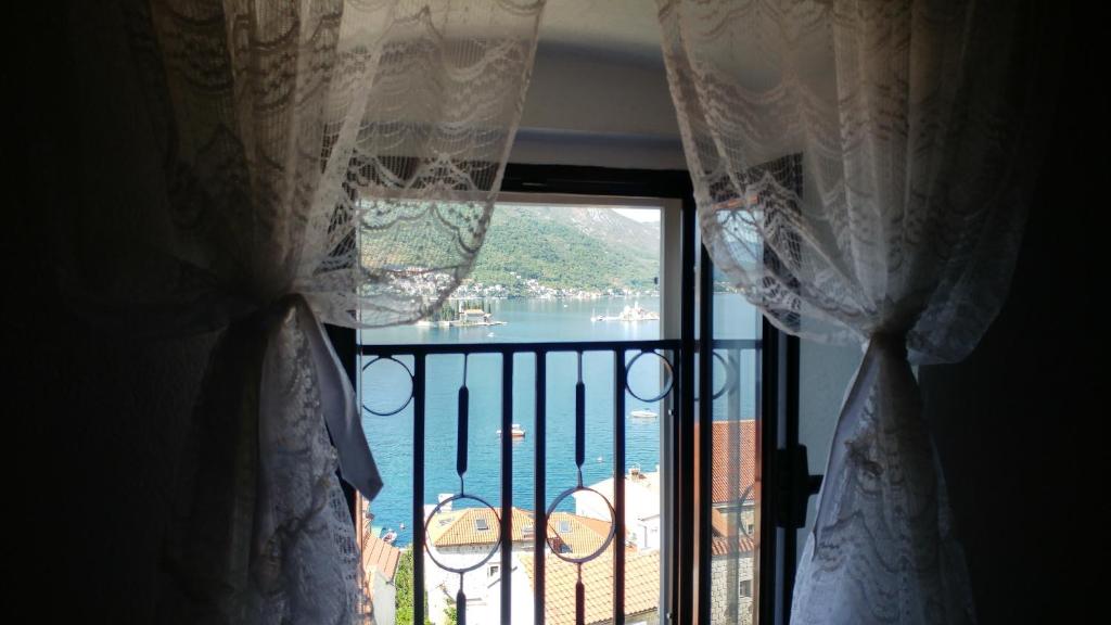 a view of the water from a window with curtains at BellaVistaZmukic Guesthouse in Perast