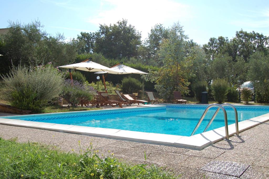 a swimming pool in a yard with an umbrella at Agriturismo Fattoria Sant'Appiano in Barberino di Val dʼElsa