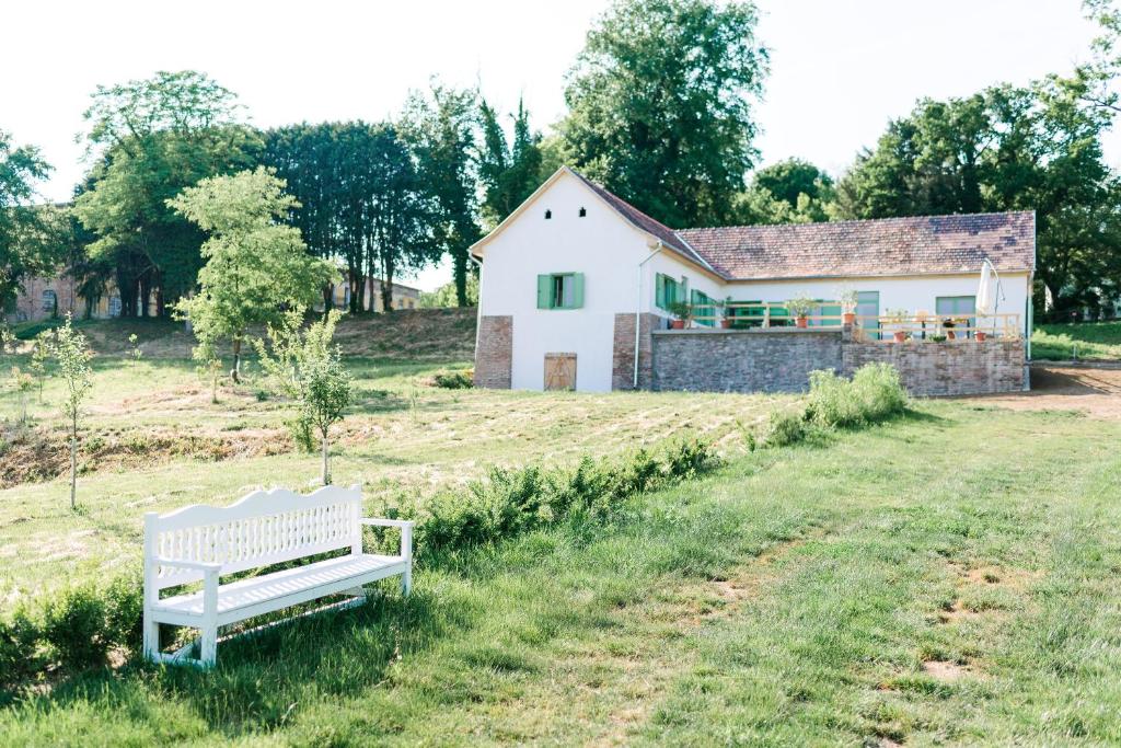 biała ławka siedząca przed domem w obiekcie Maison BOGArT w mieście Alsobogát