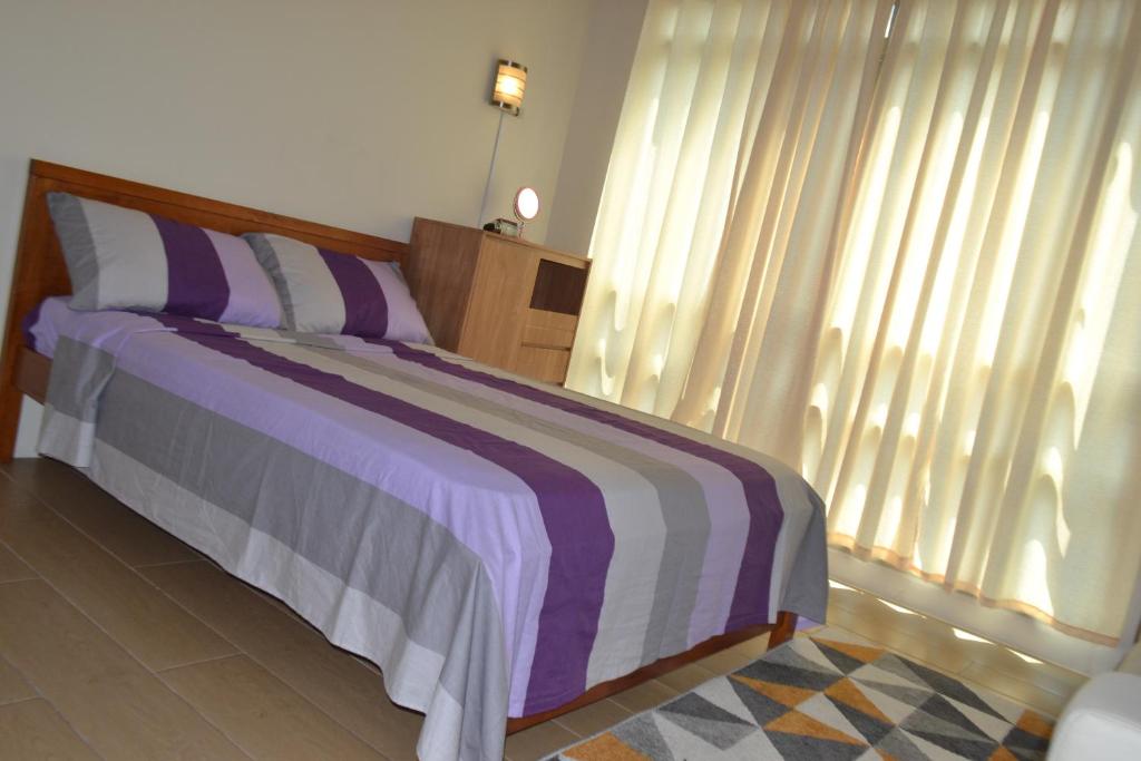 a bedroom with a bed with a purple and white blanket at Daichi Place Newport Boulevard in Manila