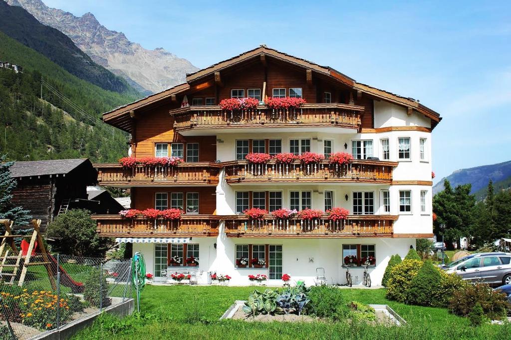 un gran edificio con flores rojas en los balcones en Apartments Arcadia, en Saas-Grund