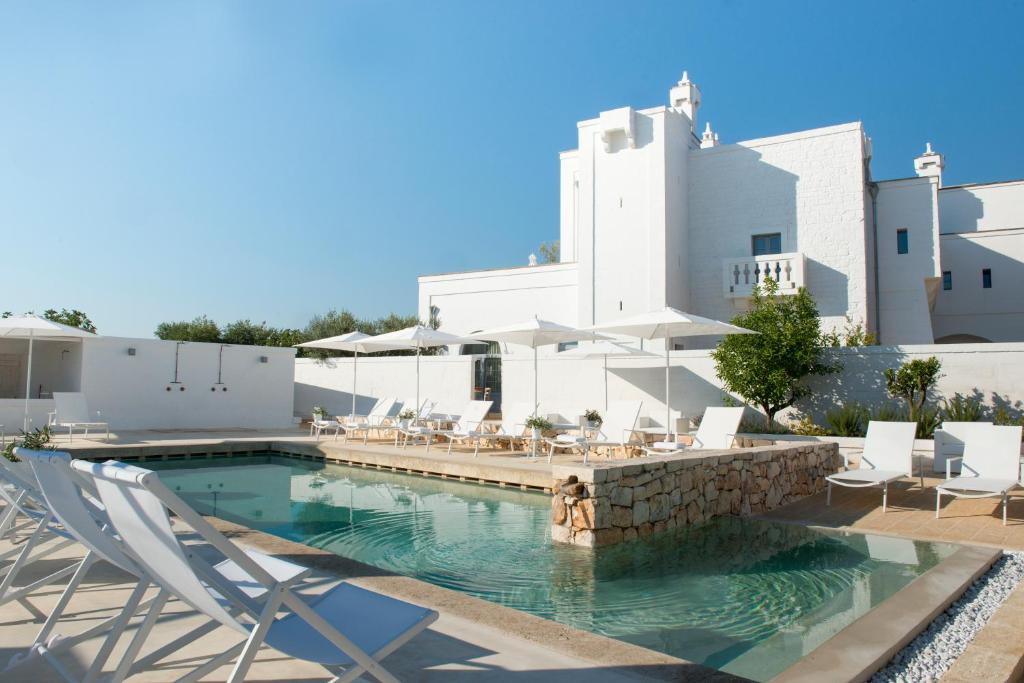 a swimming pool with chairs and a building at Masseria Le Torri in Polignano a Mare