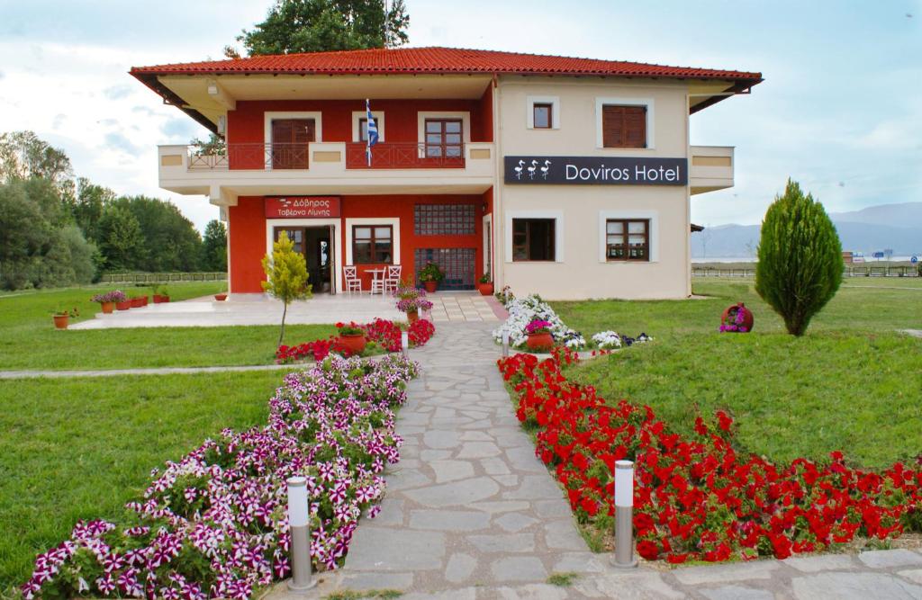 dom z czerwonymi i różowymi kwiatami przed nim w obiekcie Doviros Hotel w mieście Doirani