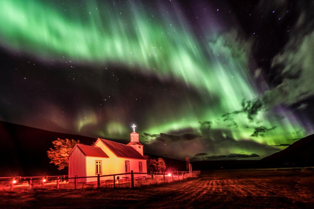 una imagen de una iglesia con luces del norte en Bólstaðarhlíð Guesthouse en Bólstaðarhlíð