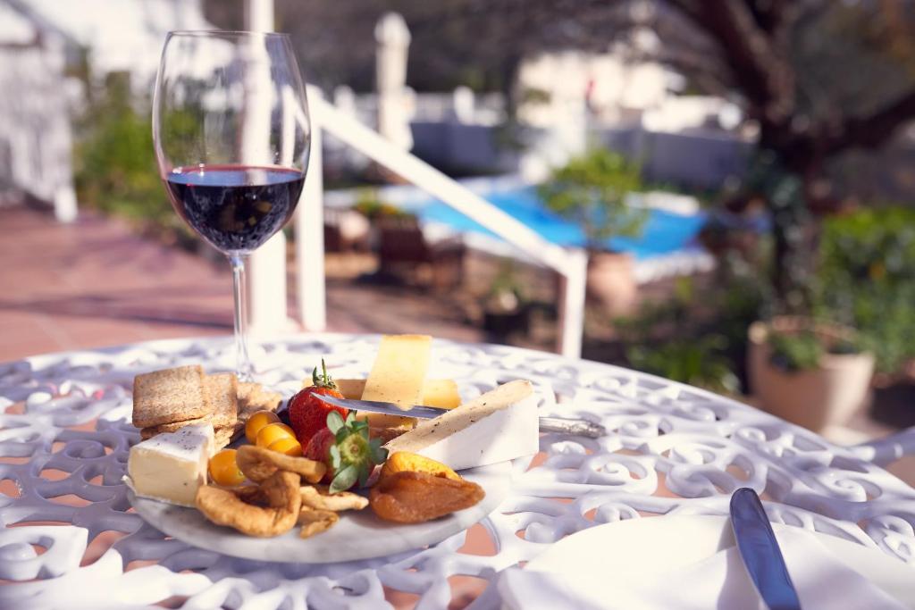 a plate of food and a glass of wine on a table at Corner House Residence in Franschhoek
