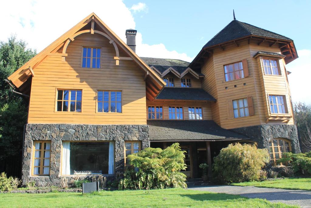 uma grande casa de madeira com um telhado de gambrel em Hotel Malalhue em Pucón