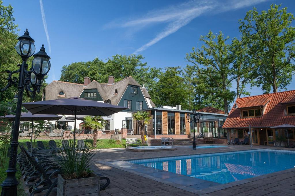 a swimming pool in front of a house at Huize Hölterhof Wellness Hotel Restaurant in Enschede