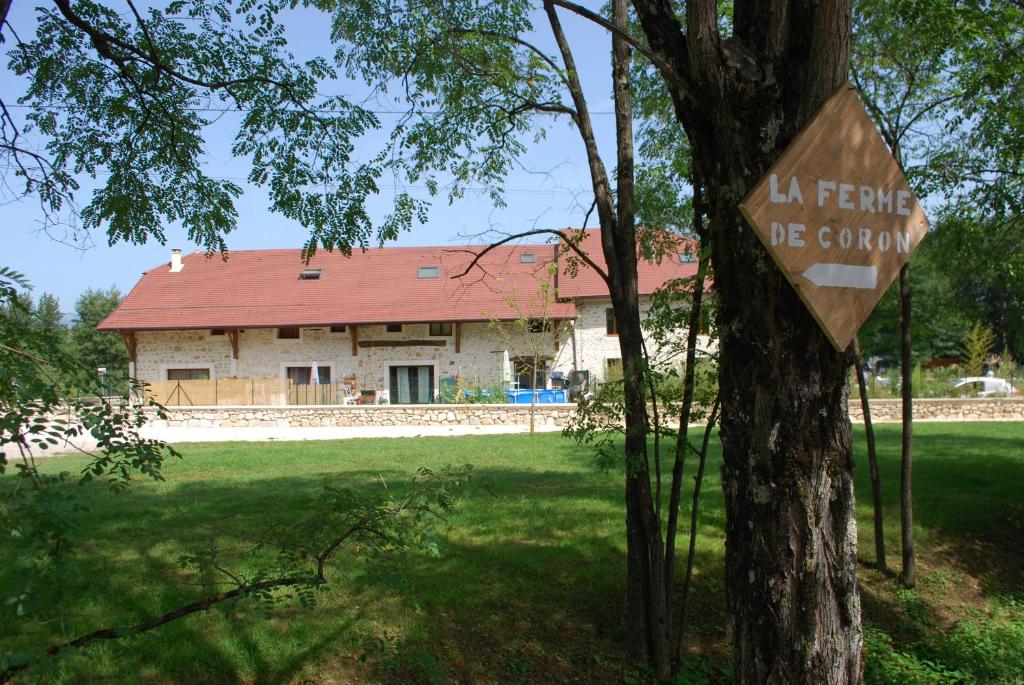 un panneau sur un arbre devant un bâtiment dans l'établissement La ferme de Coron, à Belley