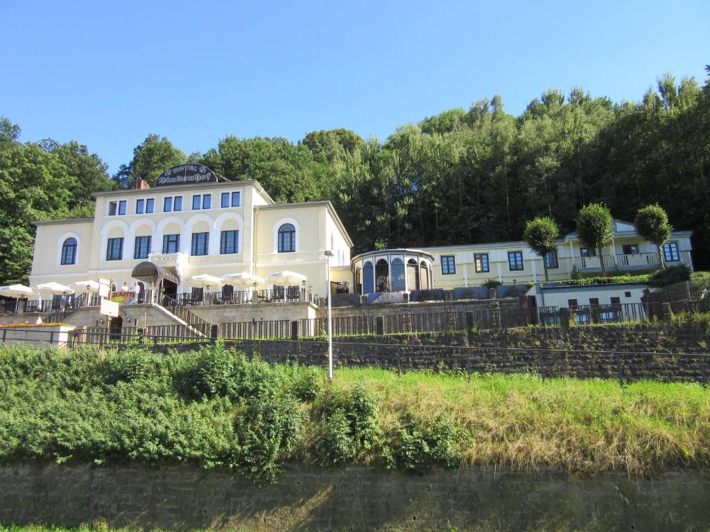 ein großes weißes Haus am Ufer eines Flusses in der Unterkunft Hotel Lindenhof in Königstein an der Elbe