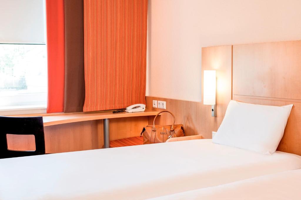a bedroom with a bed and a desk with a phone at ibis London Elstree Borehamwood in Borehamwood