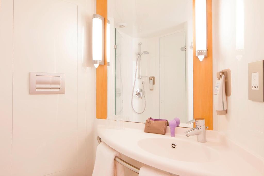 a white bathroom with a sink and a mirror at ibis London Elstree Borehamwood in Borehamwood