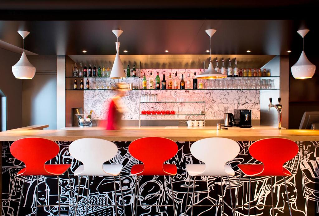a bar with red and white stools at ibis London Elstree Borehamwood in Borehamwood