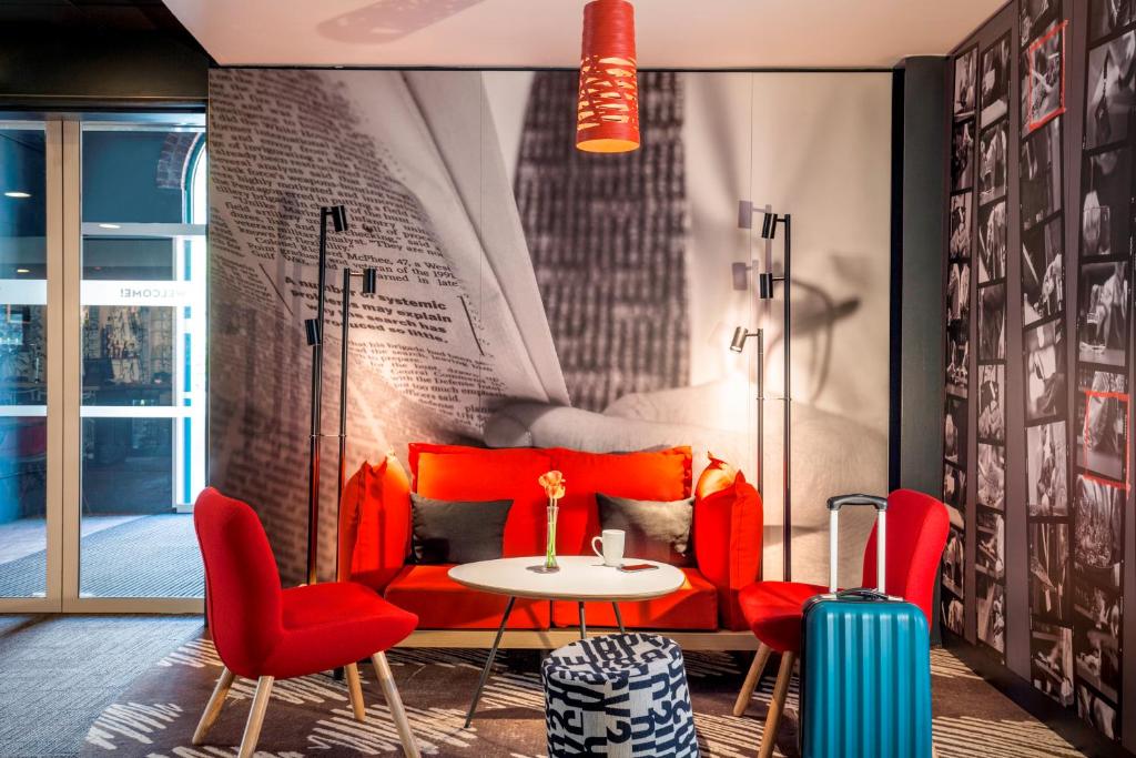 a room with a red couch and chairs and a table at ibis London Elstree Borehamwood in Borehamwood