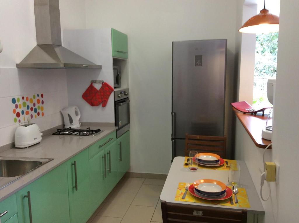 a kitchen with green cabinets and a stainless steel refrigerator at Plaisir de vivre - T2 Proche CHUM La Meynard in Fort-de-France