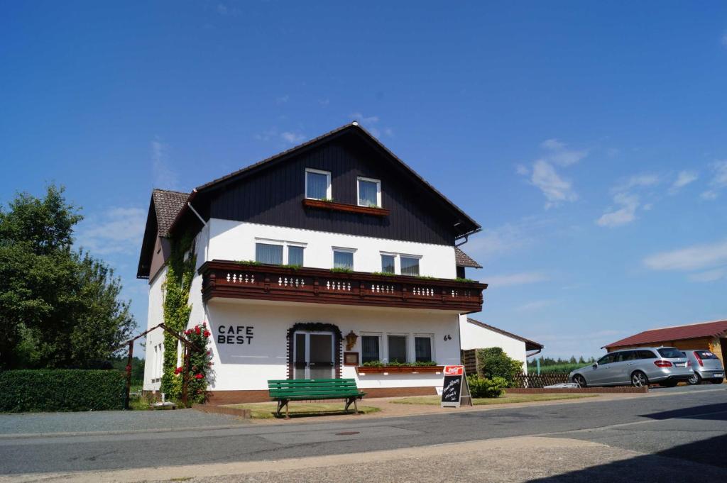 ein weißes Haus mit einer grünen Bank davor in der Unterkunft Cafe Best  Ferienwohnung in Bullau
