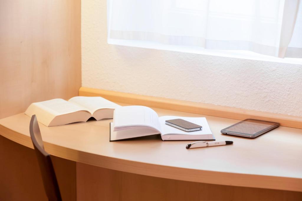 a desk with two open books and a pen and a wallet at ibis London Elstree Borehamwood in Borehamwood