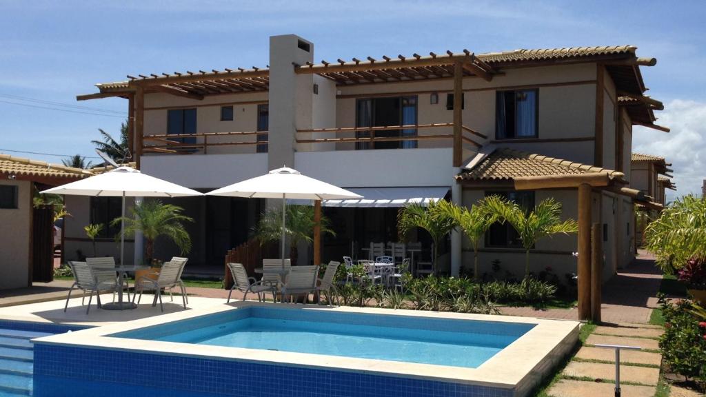 a villa with a swimming pool in front of a house at Village Reserva das Ilhas - Itacimirim in Itacimirim