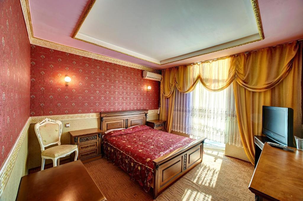Habitación de hotel con cama, escritorio y TV. en Hotel Izvora, en Ruse