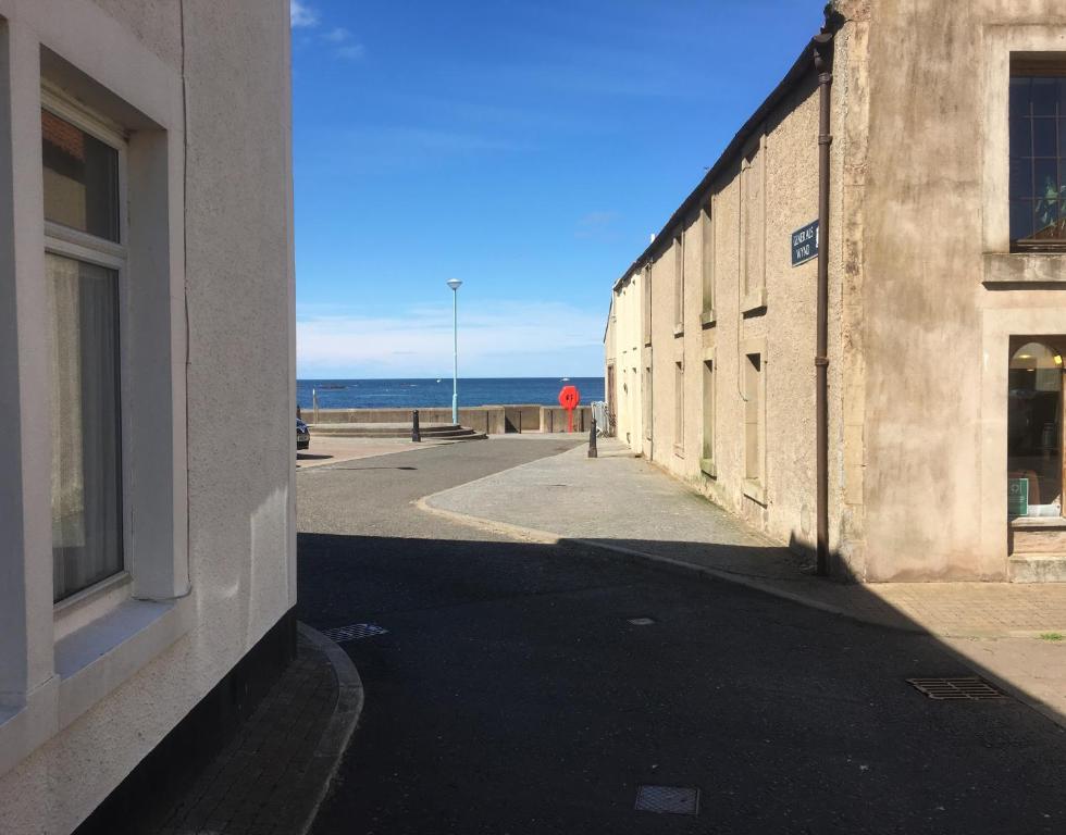 an empty street next to a building and the ocean at 1 St Ellas House Apartment in Eyemouth