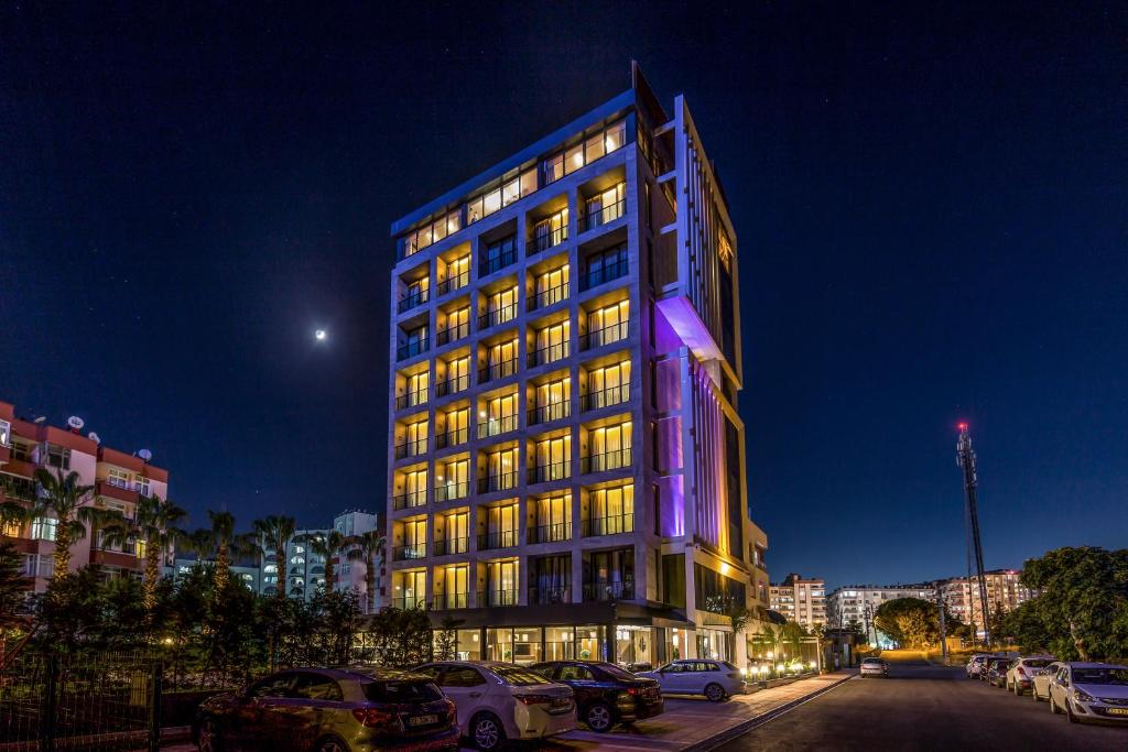 a lit up building with cars parked in a parking lot at Vista Boutique Hotel in Mezitli