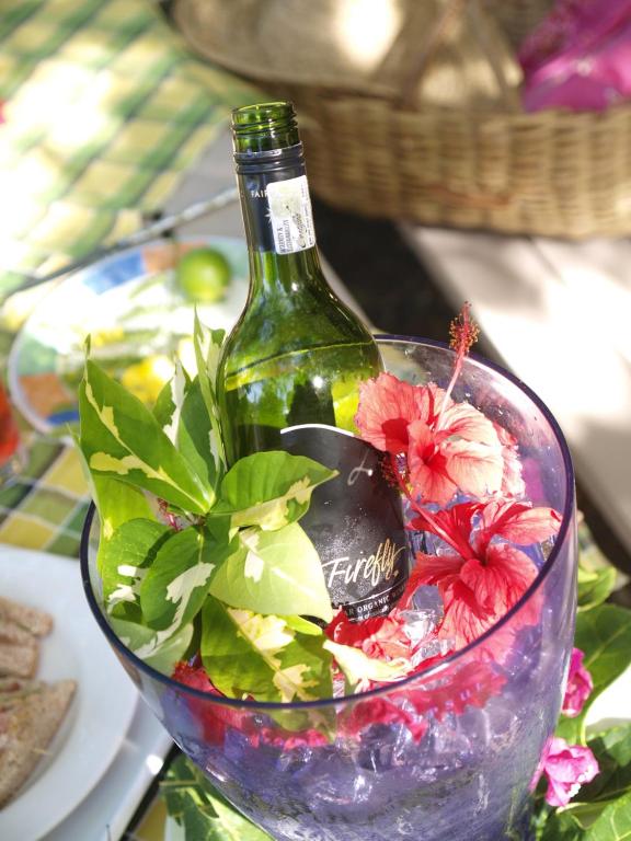a bottle of wine sitting in a bowl with flowers at Firefly Estate Bequia in Crescent Beach