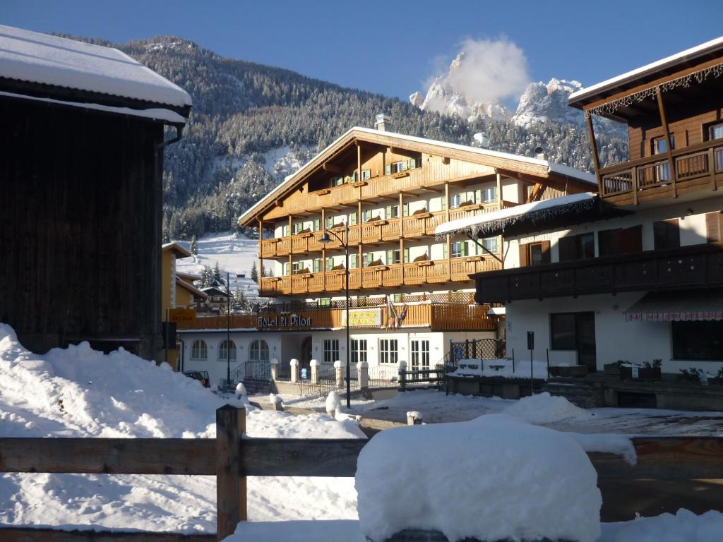 a large building in the snow with a mountain at Hotel El Pilon in Pozza di Fassa