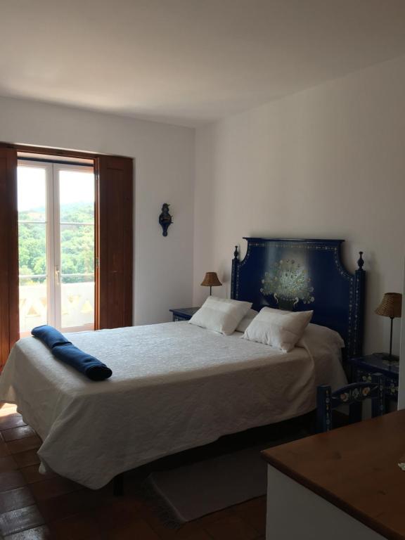 a bedroom with a large bed with a blue headboard at Amieira Agroturismo in Odemira