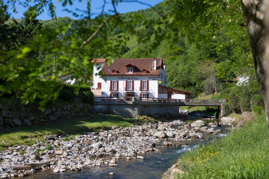 a house next to a river with rocks at Les Sources de La Nive in Esterençuby