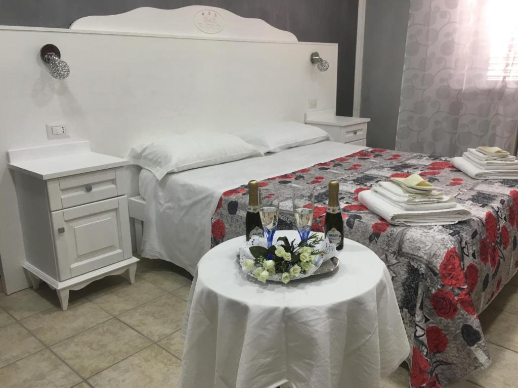 1 dormitorio con 1 cama y 2 mesas con botellas de vino en Il Rifugio di Dante, en Sinalunga