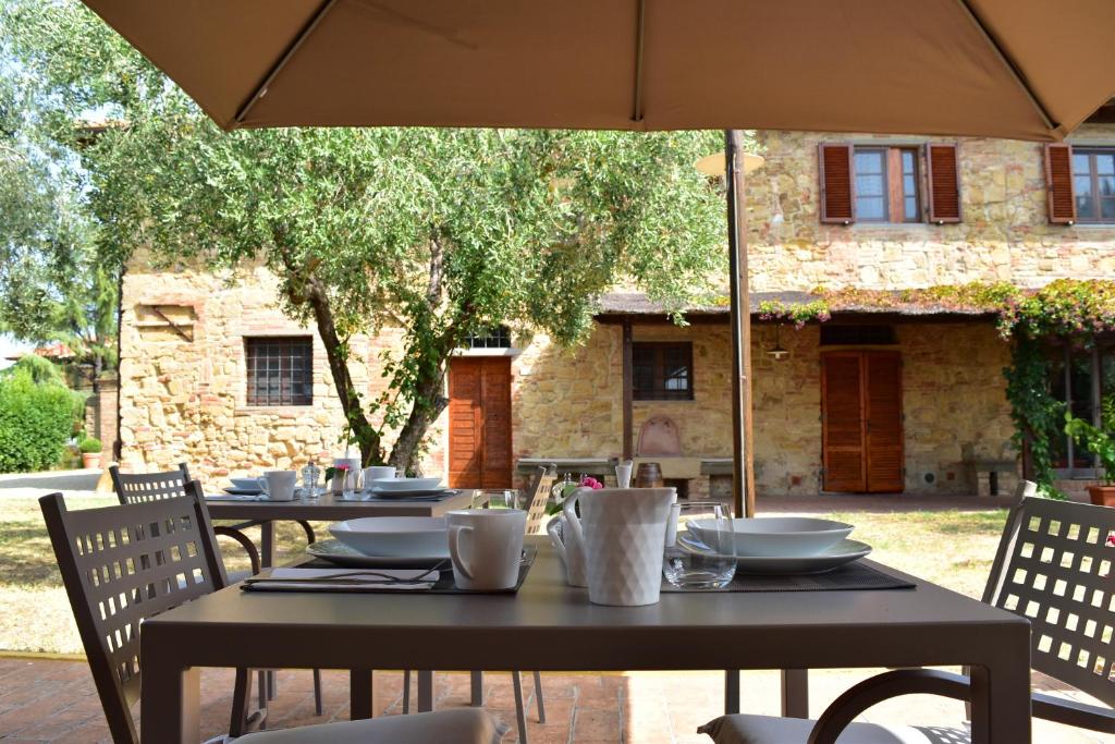 two tables with chairs and an umbrella in front of a building at Villa San Michele in Barberino di Val dʼElsa