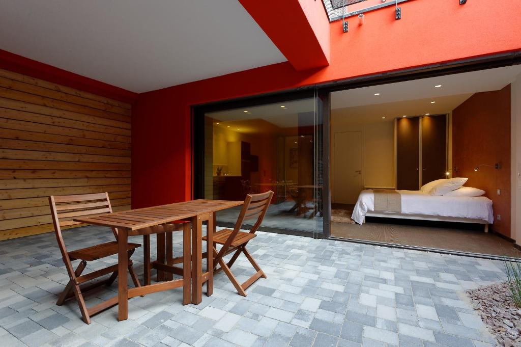 a wooden table and chairs on a patio with a bedroom at The One Apartments in Ribeauvillé