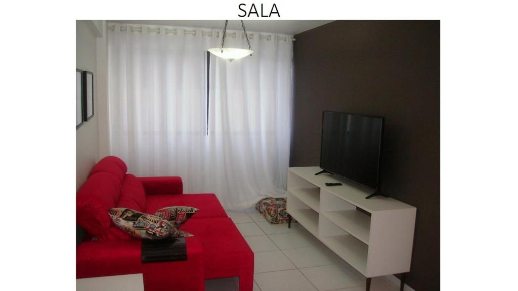 a living room with a red couch and a tv at Apartamento Ametista in Maceió