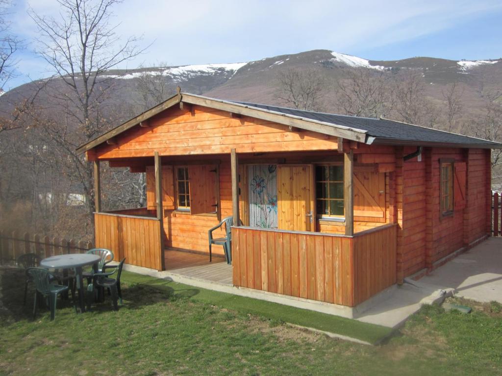 Cabaña de madera con mesa y sillas en un patio en CABAÑAS LAGO DE SANABRIA, en Vigo de Sanabria