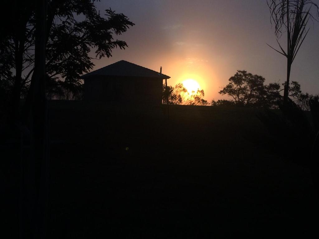 a sunset over a house with the sun in the background at Magnificat Cottage in Cunha