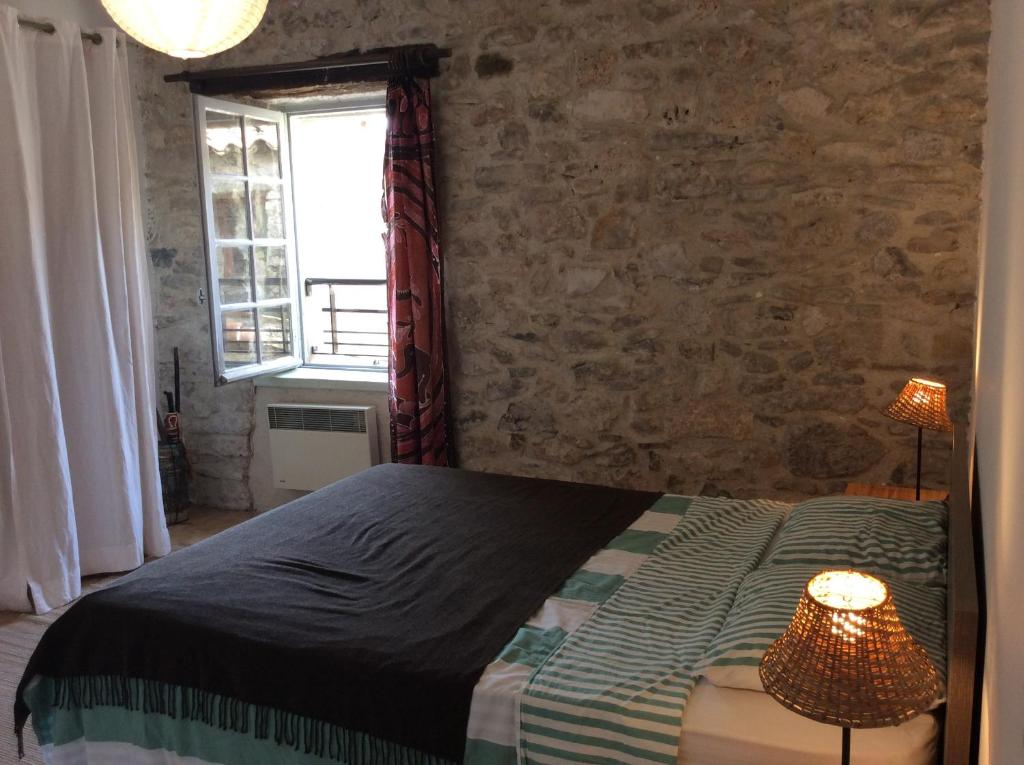 Un dormitorio con una cama y una pared de ladrillo. en Maison Ancienne Minervois, en La Caunette