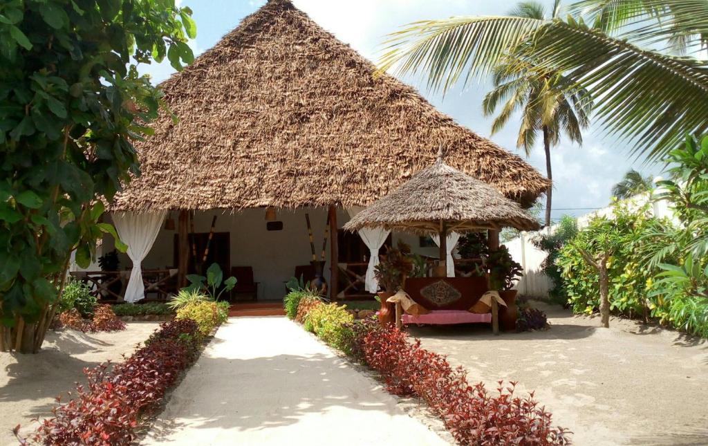 a house with a straw hut with a palm tree at Casa Carlotta & Villa in Nungwi