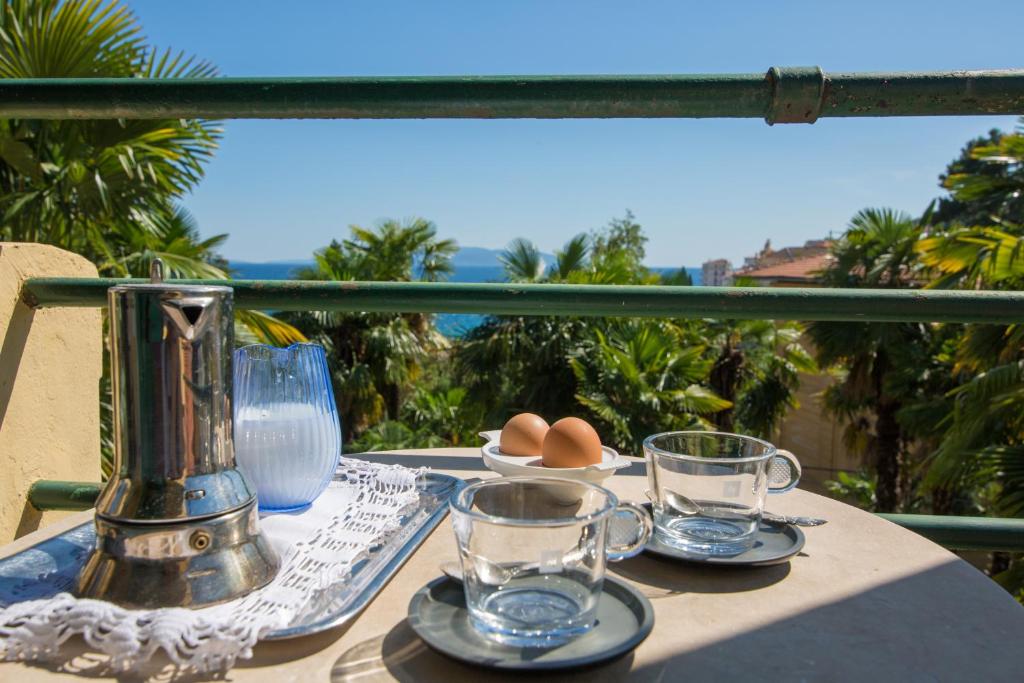 a table with plates and glasses on a balcony at Piano Nobile & Penthouse in Villa Near Beach in Opatija