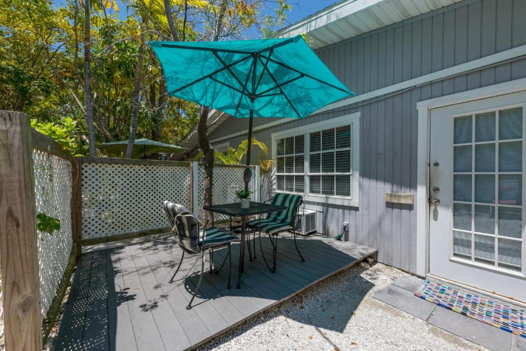 a patio with a table and two chairs and a blue umbrella at Tarpon Tale Inn in Sanibel